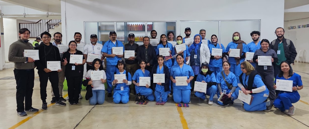 A photo of a group of people most of who are wearing matching matching blue scrubs and all are holding certificates