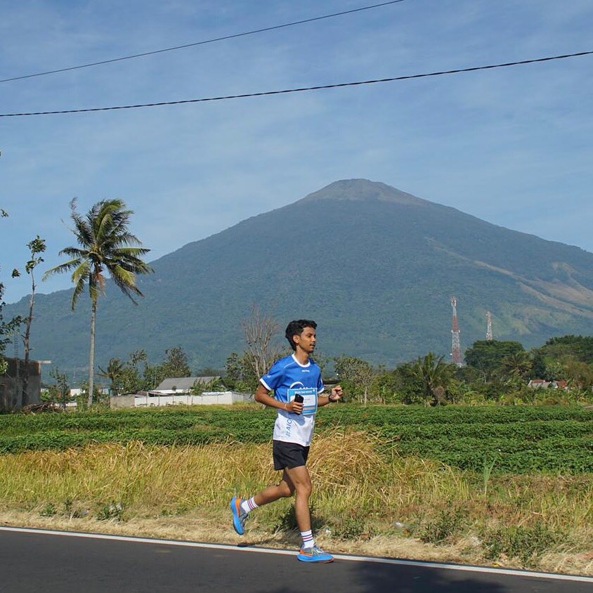 A man running on a road with a mountain in the background