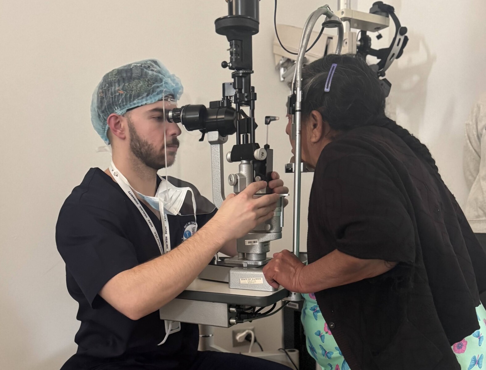An elderly woman stands for an eye exam.