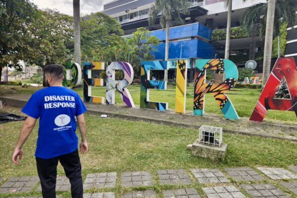 A Humanity First disaster relief volunteer surveys a central location in front of the city sign for Pereira, Colombia.